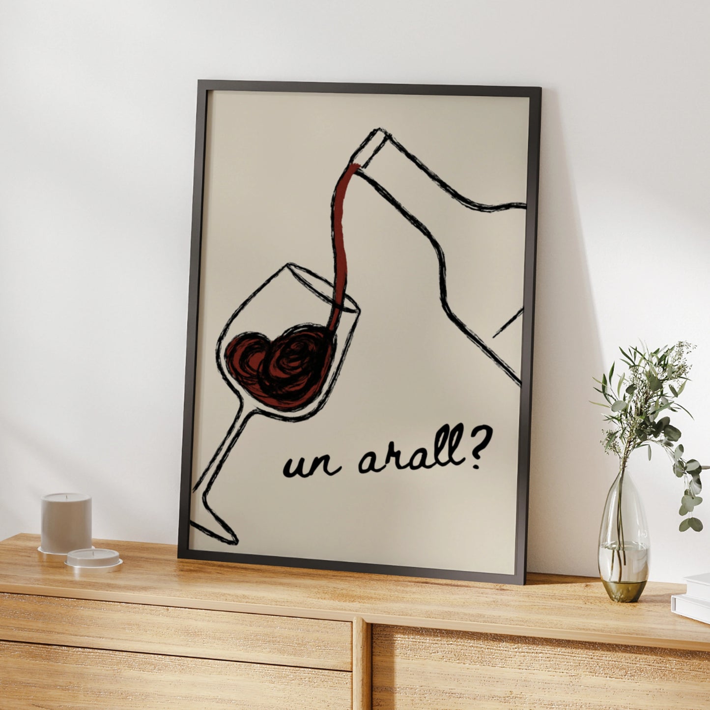 Red wine pouring into a glass with the Welsh words un arall on cream