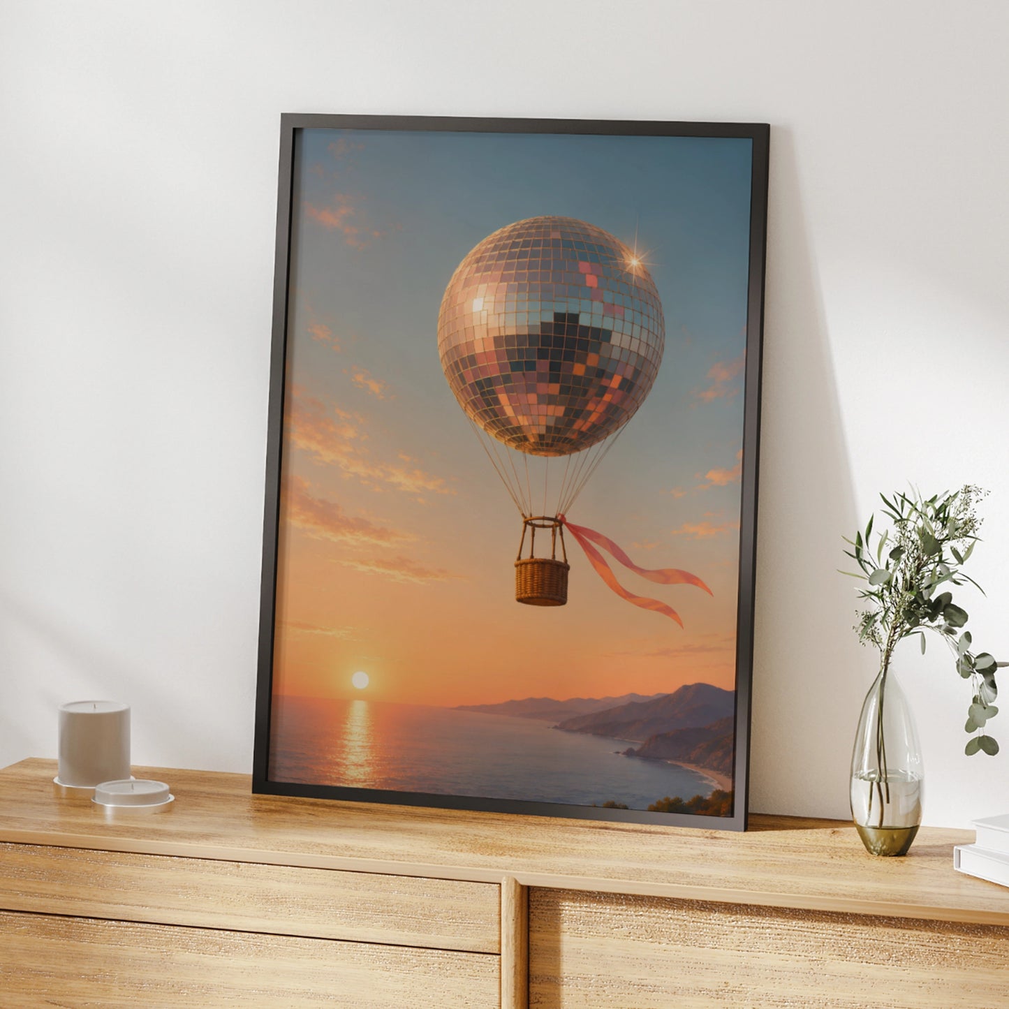 Disco ball hot-air balloon floating above a peach and pink coastal sunset